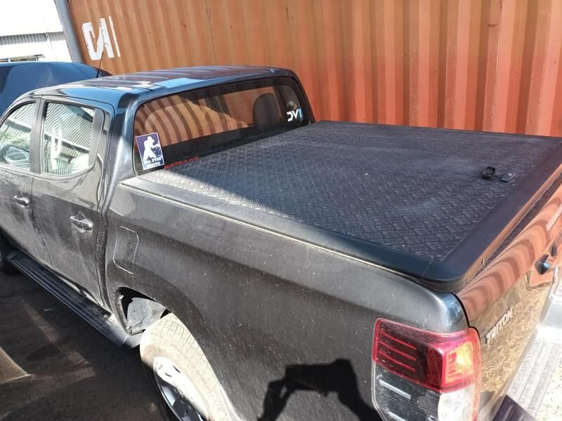 A Black Truck With a Black Bed Cover is Parked in Front of a Shipping Container — South West 4WD Wreckers In Harristown, QLD
