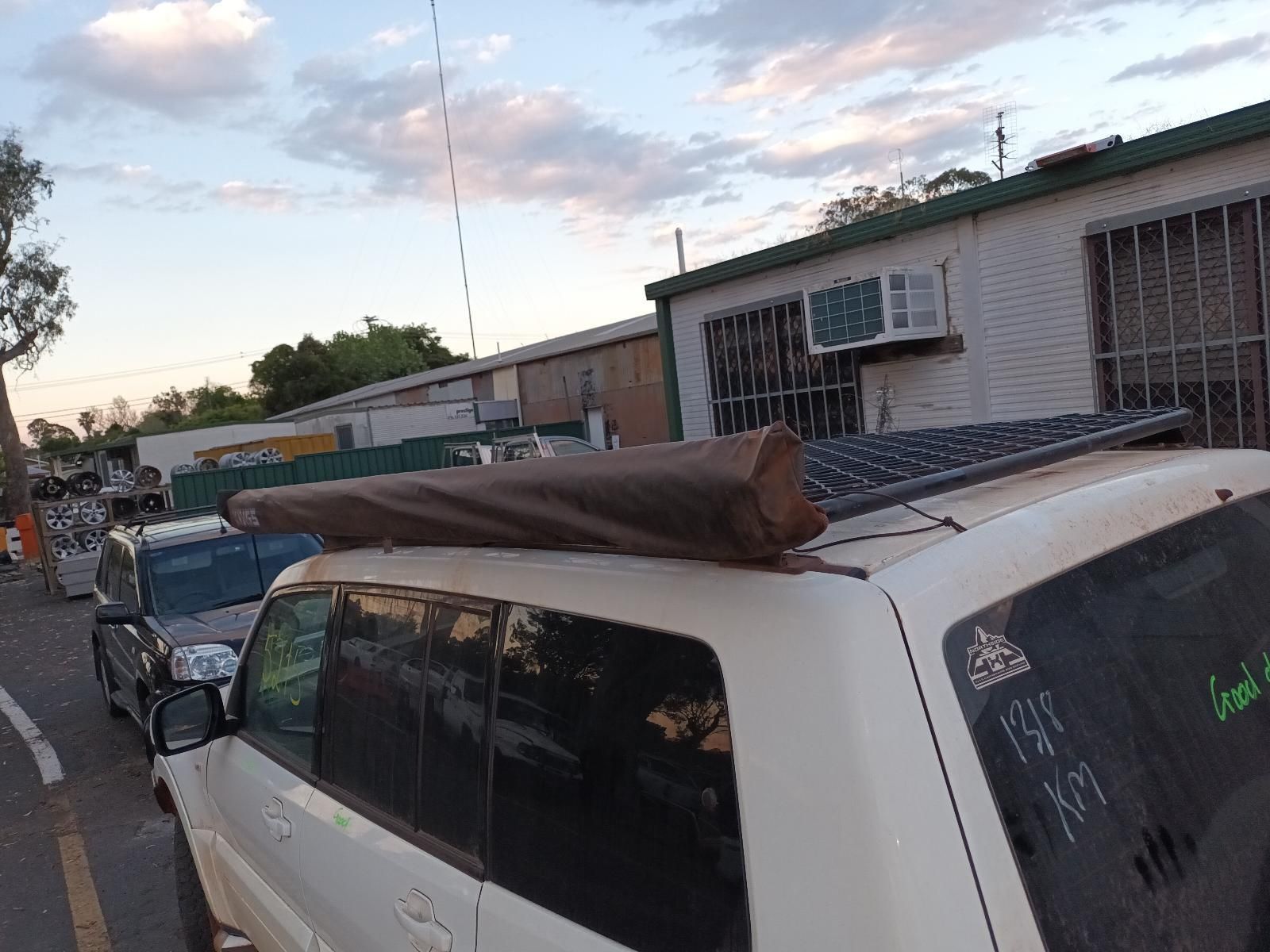 A White Suv With a Tent on Top of It is Parked on the Side of the Road — South West 4WD Wreckers In Brisbane, QLD
