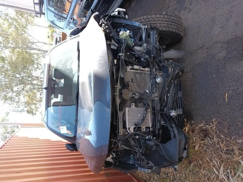 A Wrecked Car is Sitting on the Side of the Road Next to a Fence — South West 4WD Wreckers In Harristown, QLD
