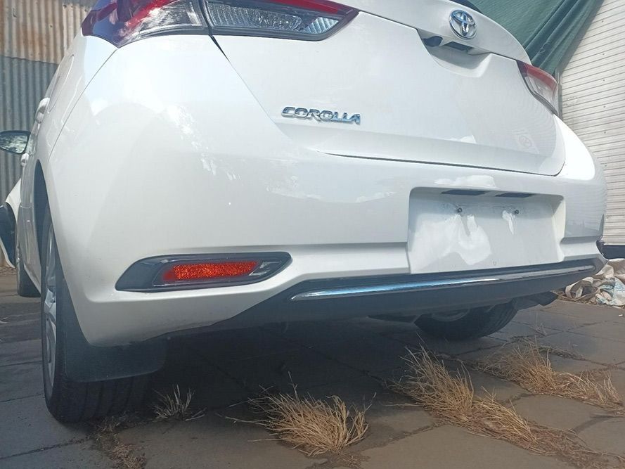 A White Toyota Corolla is Parked on a Sidewalk in Front of a Building — South West 4WD Wreckers in Harristown, QLD