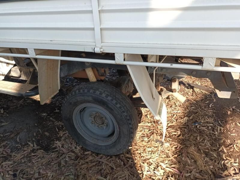 A White Truck With a Gray Tire is Parked in the Dirt — South West 4WD Wreckers In Brisbane, QLD