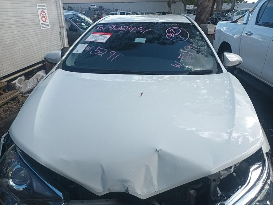 A White Car with a Damaged Hood is Parked in a Parking Lot — South West 4WD Wreckers in Harristown, QLD