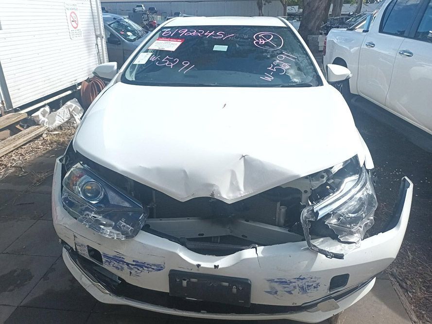 A White Car with a Damaged Front Bumper is Parked on the Side of the Road — South West 4WD Wreckers in Harristown, QLD