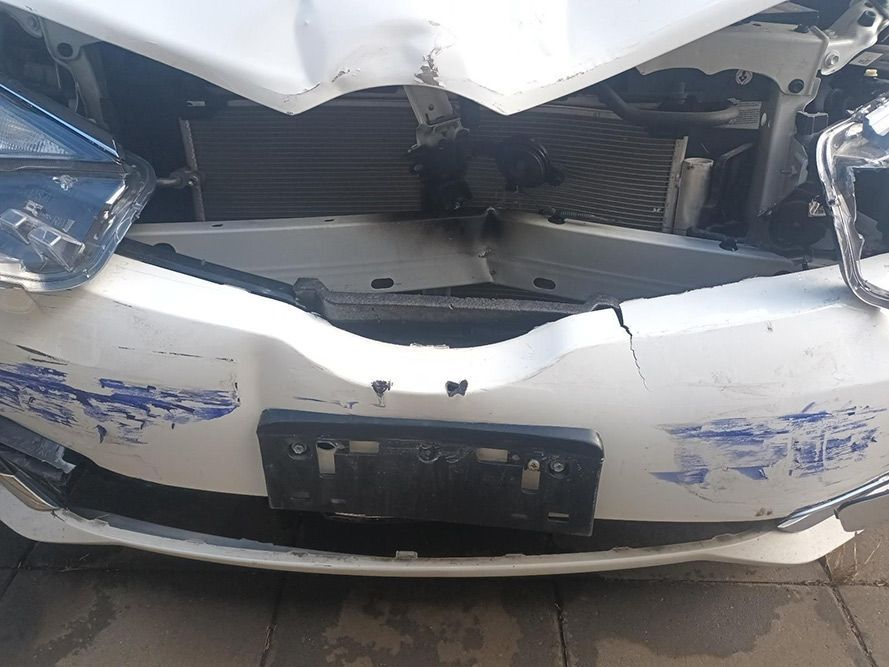 A White Car with a Damaged Front Bumper is Parked on a Sidewalk — South West 4WD Wreckers in Harristown, QLD