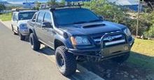 A Black Truck is Parked on the Side of the Road Next to a White Truck — South West 4WD Wreckers In Brisbane, QLD