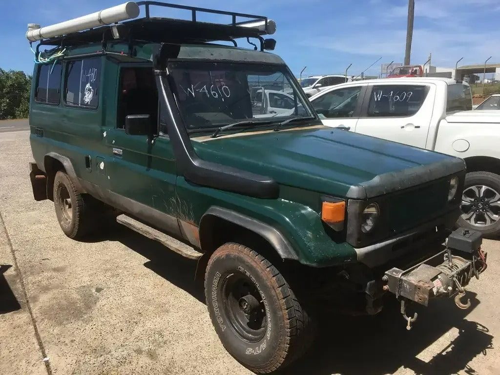 A Green Jeep With a Tent on Top of It is Parked in a Parking Lot — South West 4WD Wreckers In Brisbane, QLD