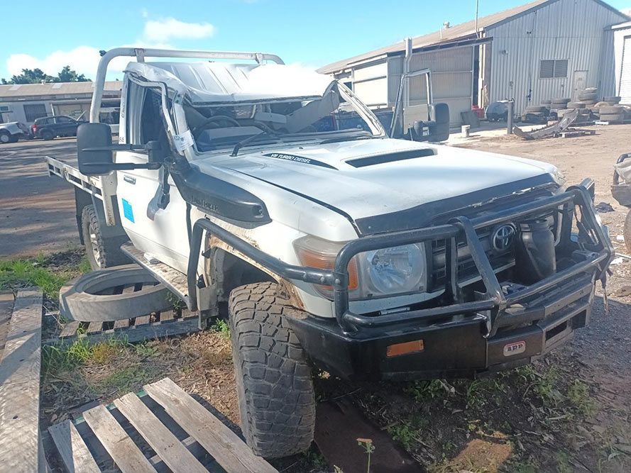 A White Truck is Parked in a Dirt Lot Next to a Wooden Pallet — South West 4WD Wreckers in Harristown, QLD