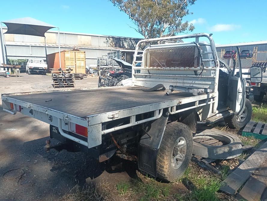 A White Truck with a Flat Bed is Parked in a Yard — South West 4WD Wreckers in Harristown, QLD