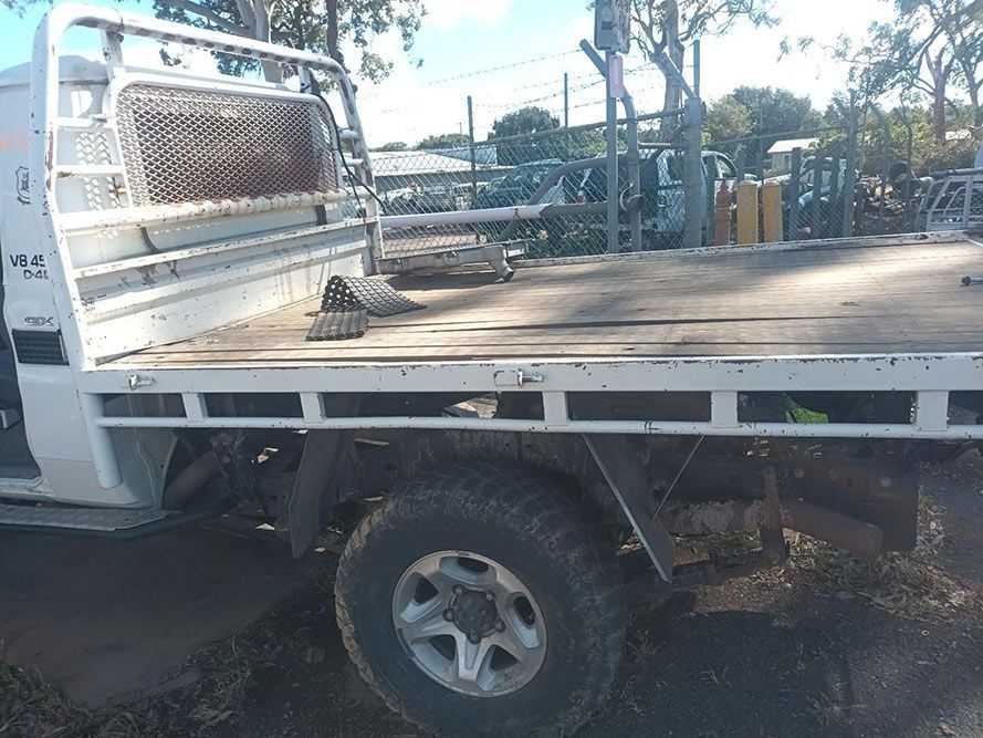 A White Truck with a Flat Bed is Parked on the Side of the Road — South West 4WD Wreckers in Harristown, QLD