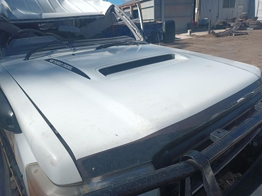 The Hood of a White Truck is Sitting in a Parking Lot — South West 4WD Wreckers in Harristown, QLD