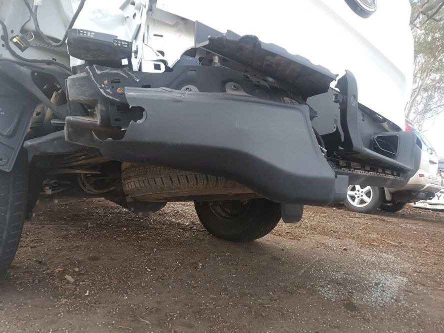 A White Truck with a Broken Bumper is Parked in a Dirt Lot — South West 4WD Wreckers in Harristown, QLD