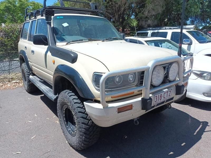 A Toyota Land Cruiser is Parked Next to a White Car — South West 4WD Wreckers In Brisbane, QLD