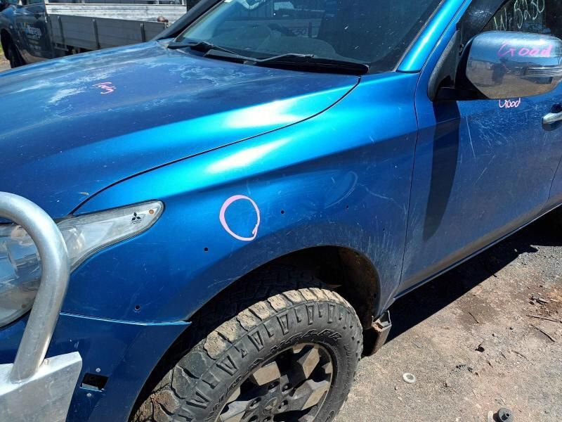 A Blue Car With a Black Tire is Parked on the Side of the Road — South West 4WD Wreckers In Brisbane, QLD