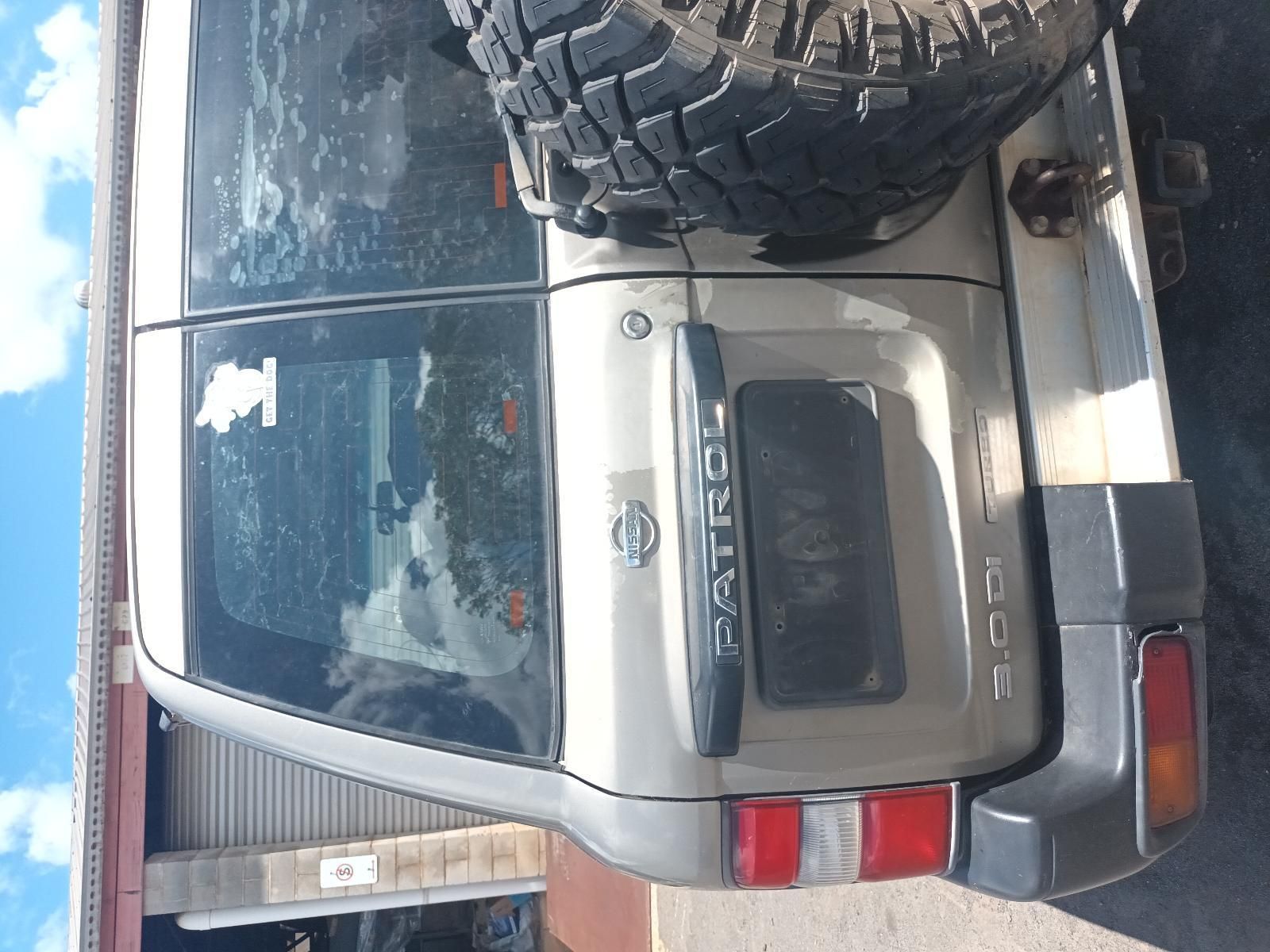A Nissan Patrol with a Large Tire on the Back is Parked in a Garage — South West 4WD Wreckers In Brisbane, QLD