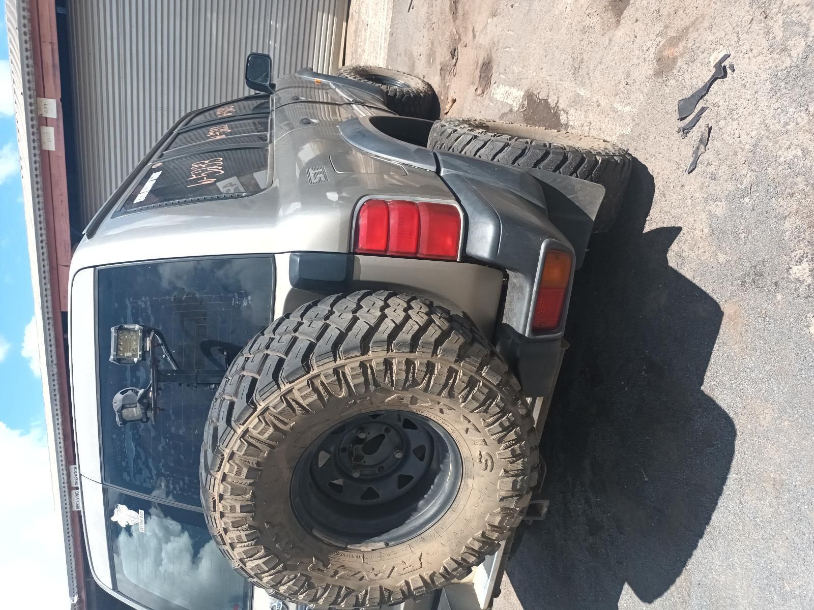 A Car with a Large Tire is Parked on the Side of the Road — South West 4WD Wreckers In Brisbane, QLD