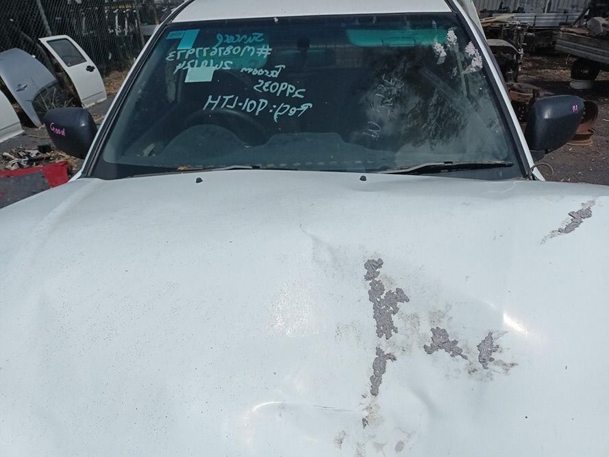 A White Car With a Broken Windshield is Parked in a Scrap Yard — South West 4WD Wreckers In Brisbane, QLD