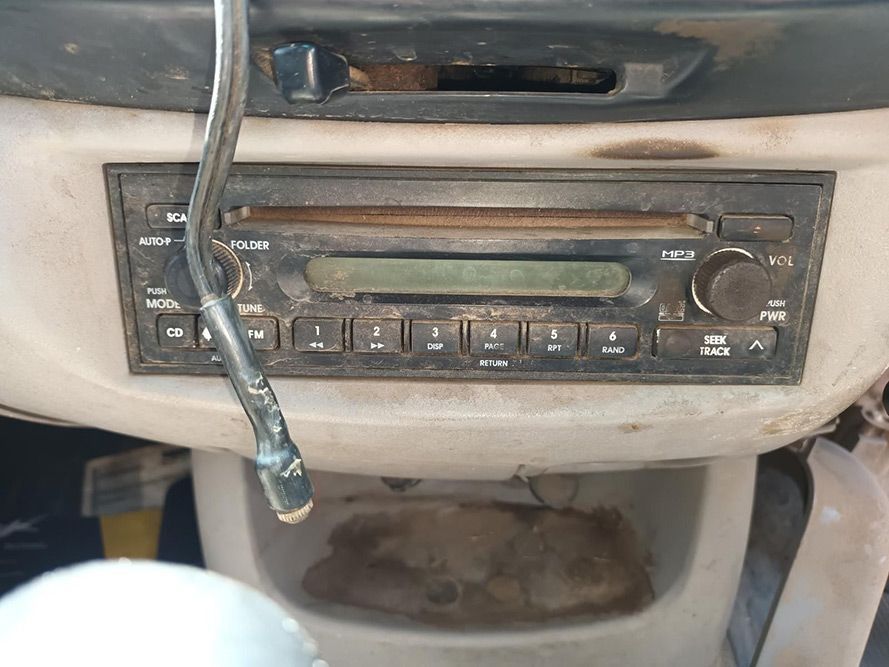 A Dirty Radio is Sitting on the Dashboard of a Car — South West 4WD Wreckers In Brisbane, QLD
