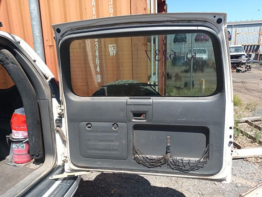 A White Car With the Back Door Open is Parked in Front of a Shipping Container — South West 4WD Wreckers In Brisbane, QLD