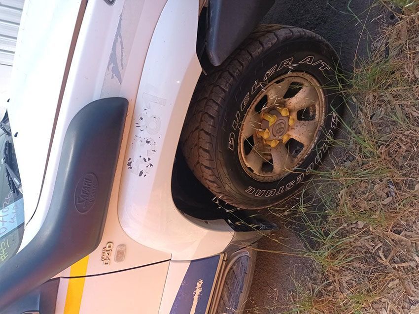A White Truck With a Yellow Tire is Parked in the Grass — South West 4WD Wreckers In Brisbane, QLD