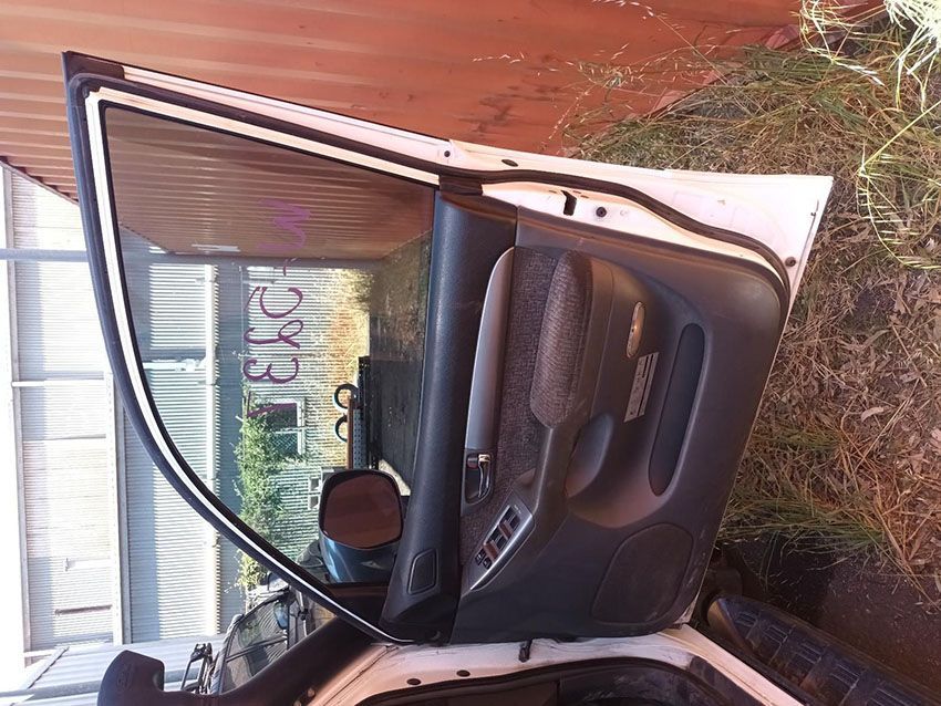 A White Car With the Door Open is Parked in Front of a Fence — South West 4WD Wreckers In Brisbane, QLD