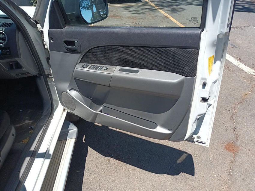A White Car With the Door Open is Parked in a Parking Lot — South West 4WD Wreckers In Brisbane, QLD