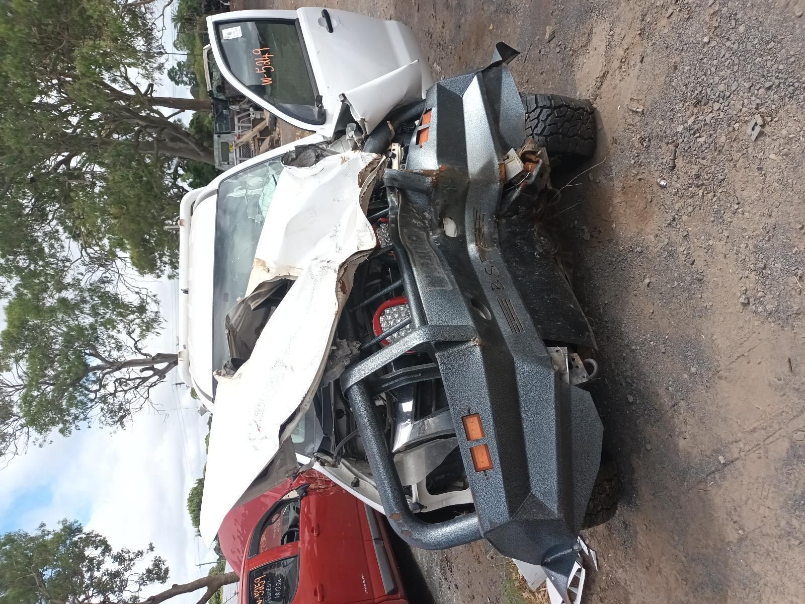 A Wrecked Truck is Parked on the Side of the Road Next to a Red Car — South West 4WD Wreckers In Brisbane, QLD