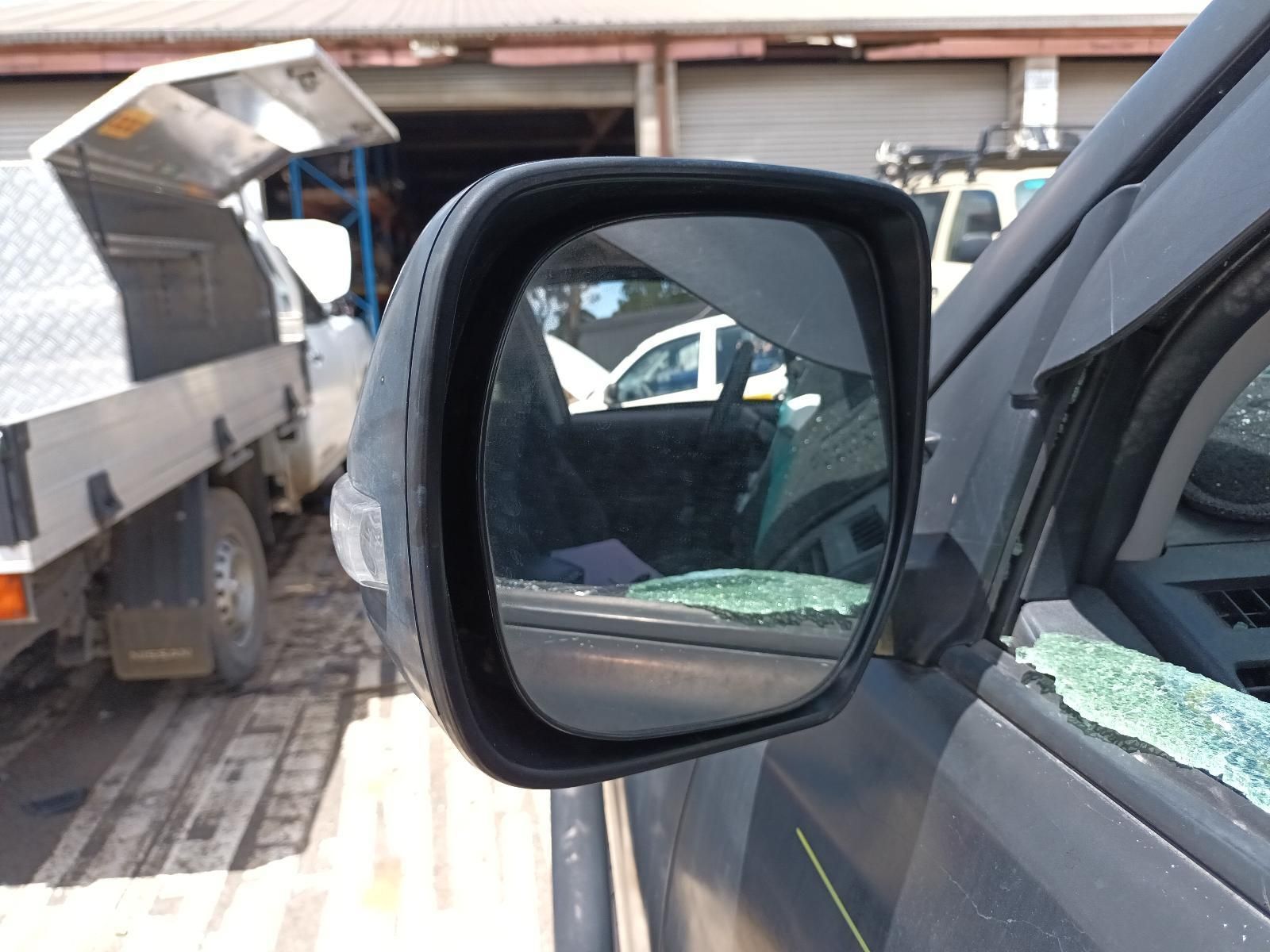 A Car with a Broken Side Mirror is Parked in Front of a Garage — South West 4WD Wreckers In Brisbane, QLD