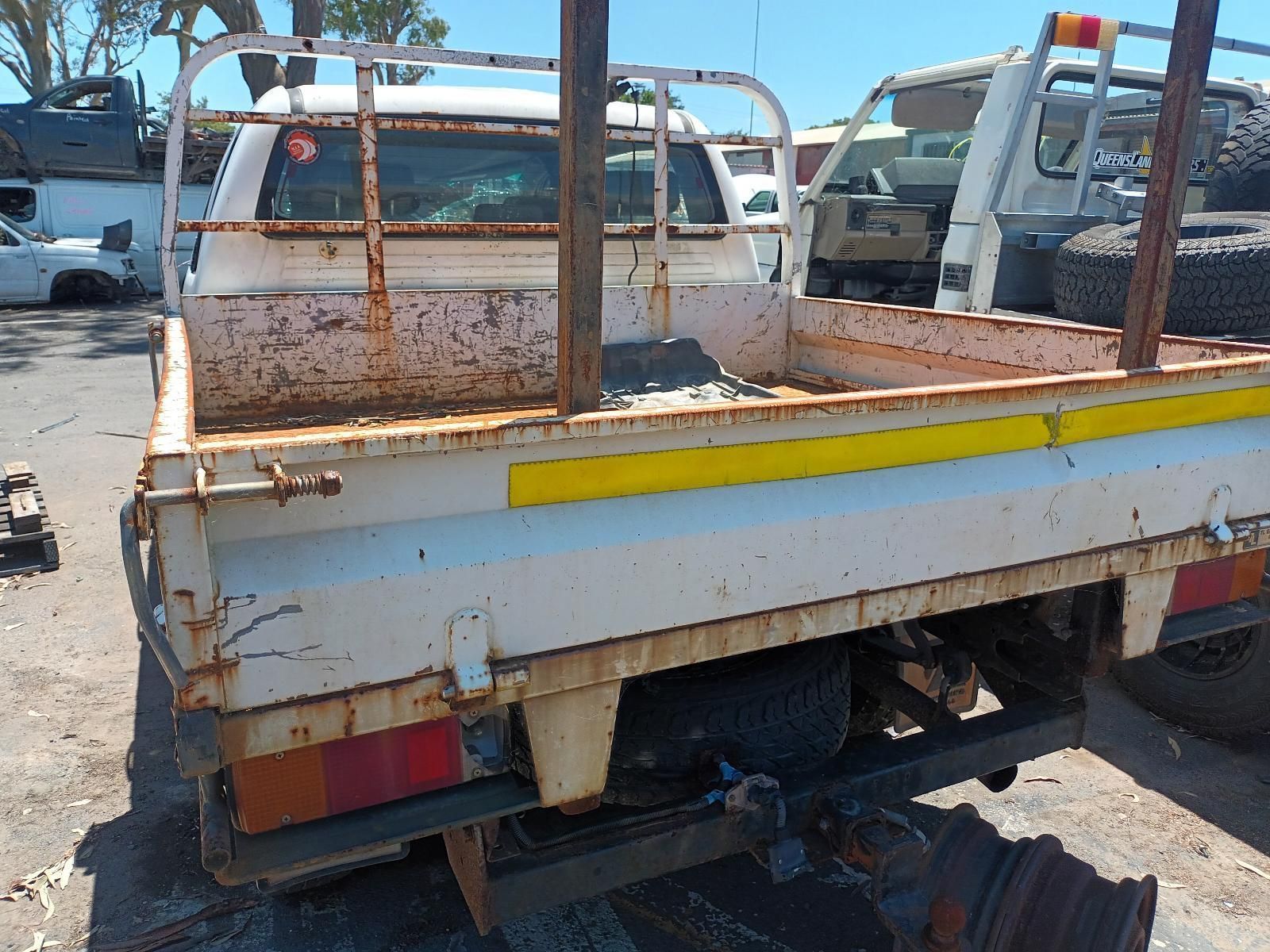 A White Truck with a Yellow Stripe on the Back is Parked in a Parking Lot — South West 4WD Wreckers in Harristown, QLD
