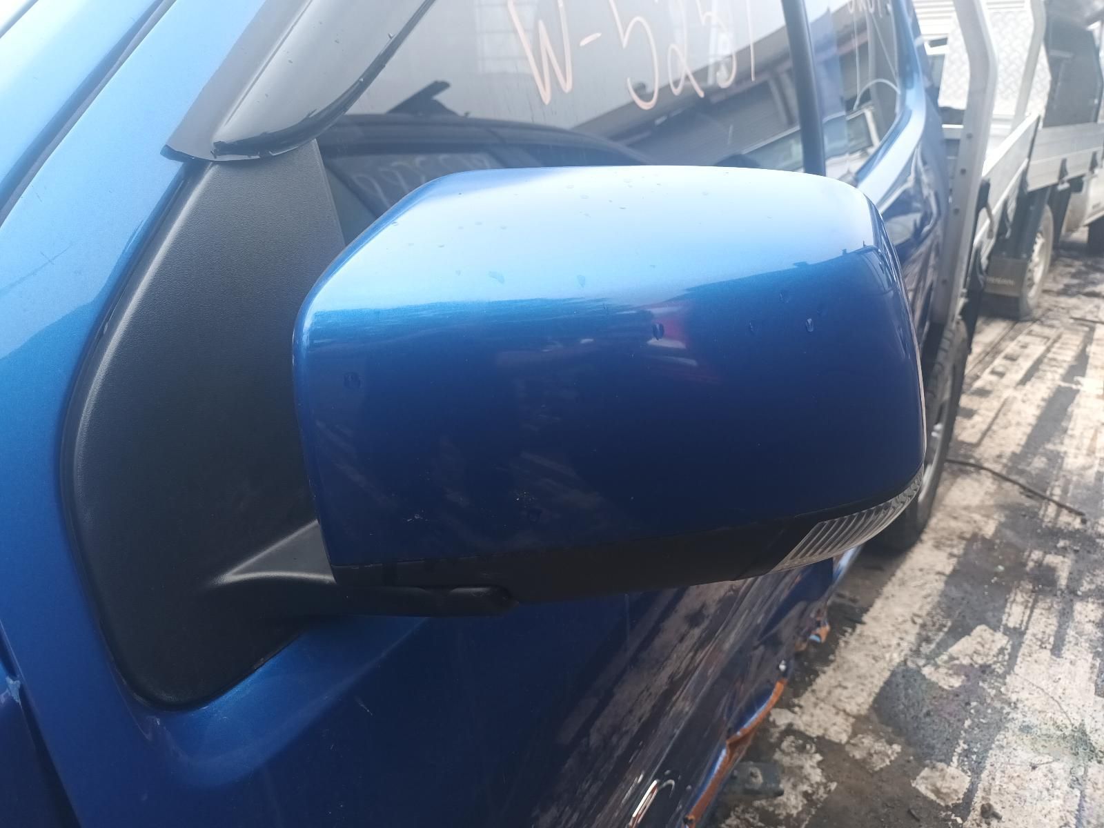 A Blue Car with a Black Side Mirror is Parked on the Side of the Road — South West 4WD Wreckers In Brisbane, QLD