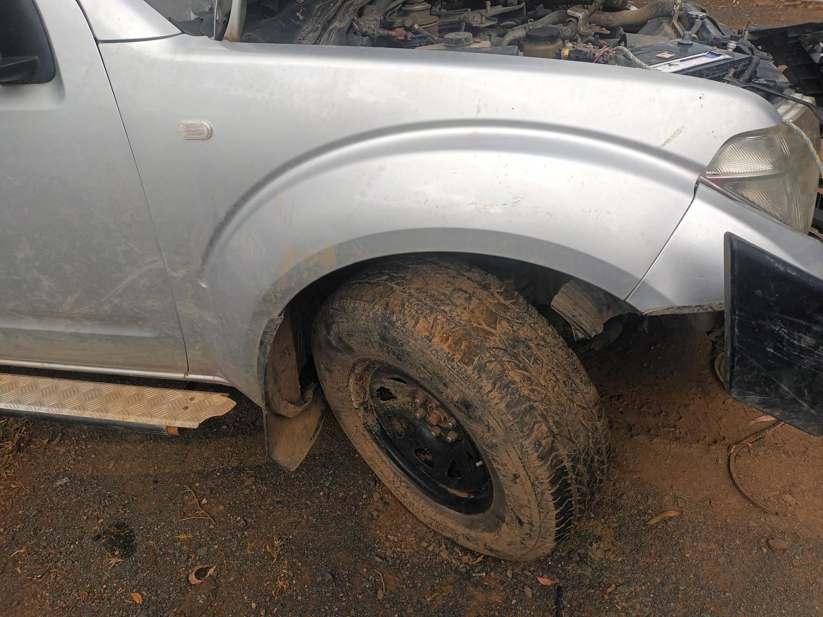 A Silver Truck with a Muddy Tire is Parked on a Dirt Road — South West 4WD Wreckers In Brisbane, QLD