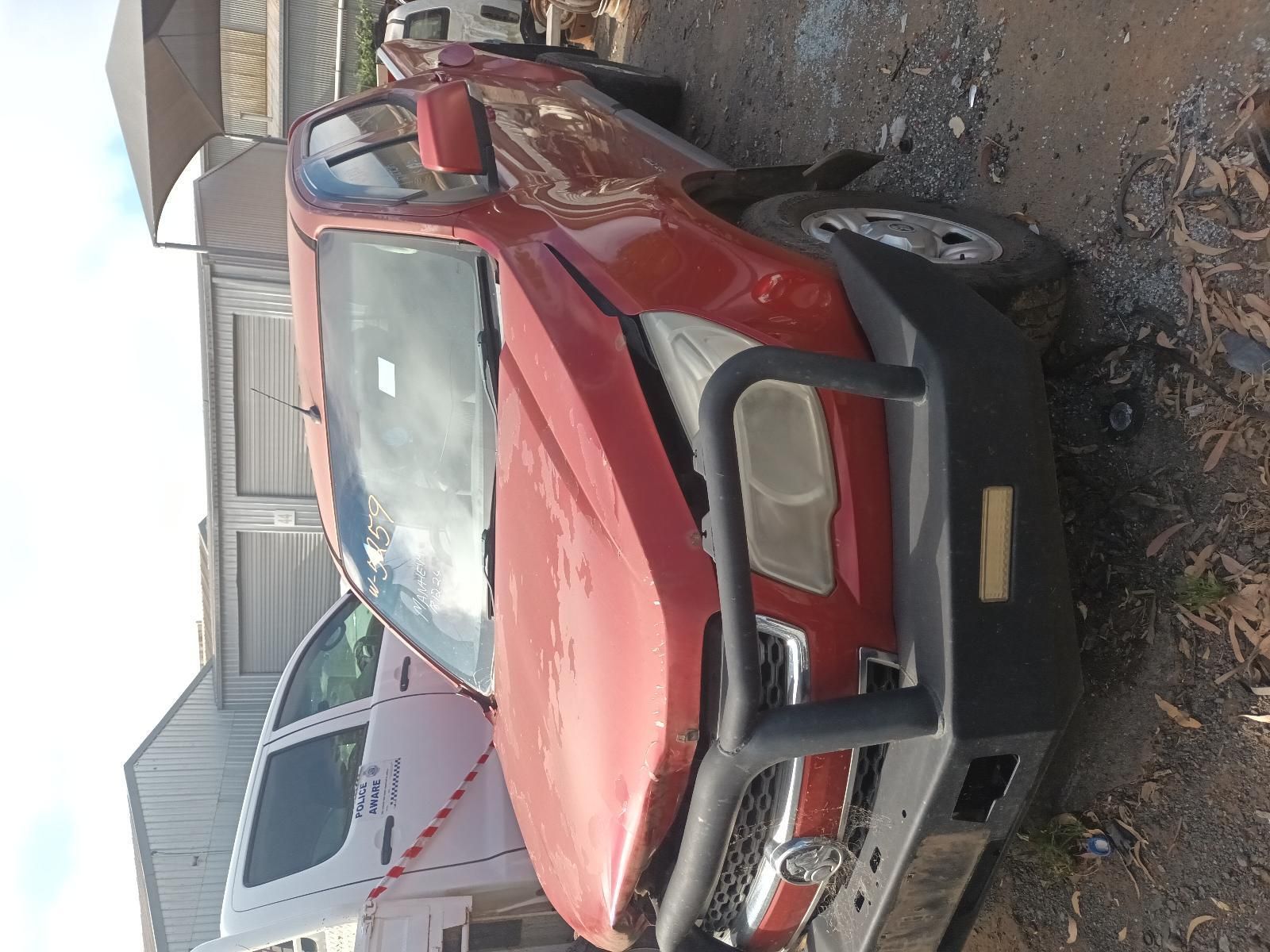 A Red Car with a Black Bumper is Parked on the Side of the Road — South West 4WD Wreckers In Brisbane, QLD