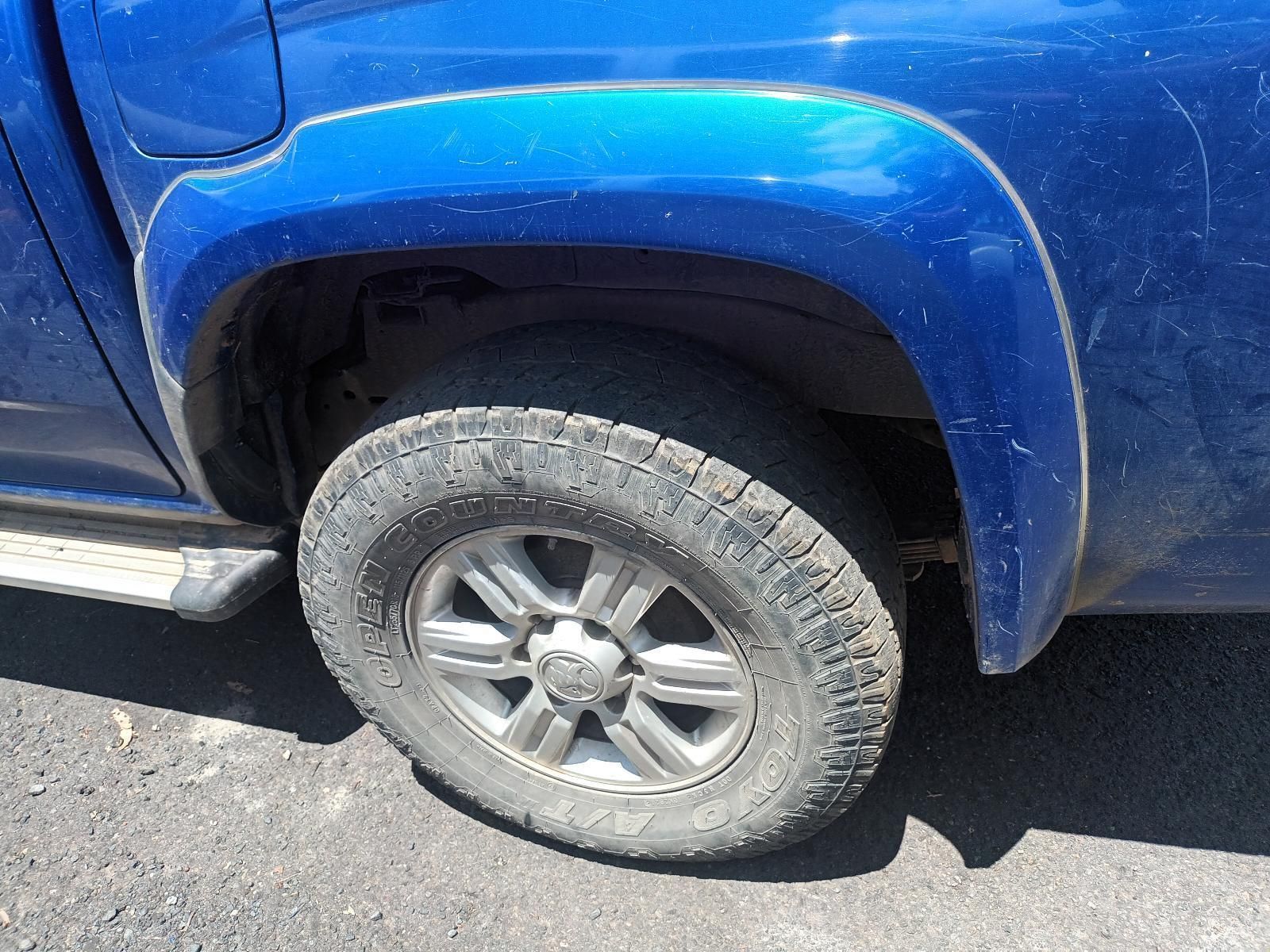 A Blue Truck with a Black Tire is Parked on the Side of the Road — South West 4WD Wreckers In Brisbane, QLD