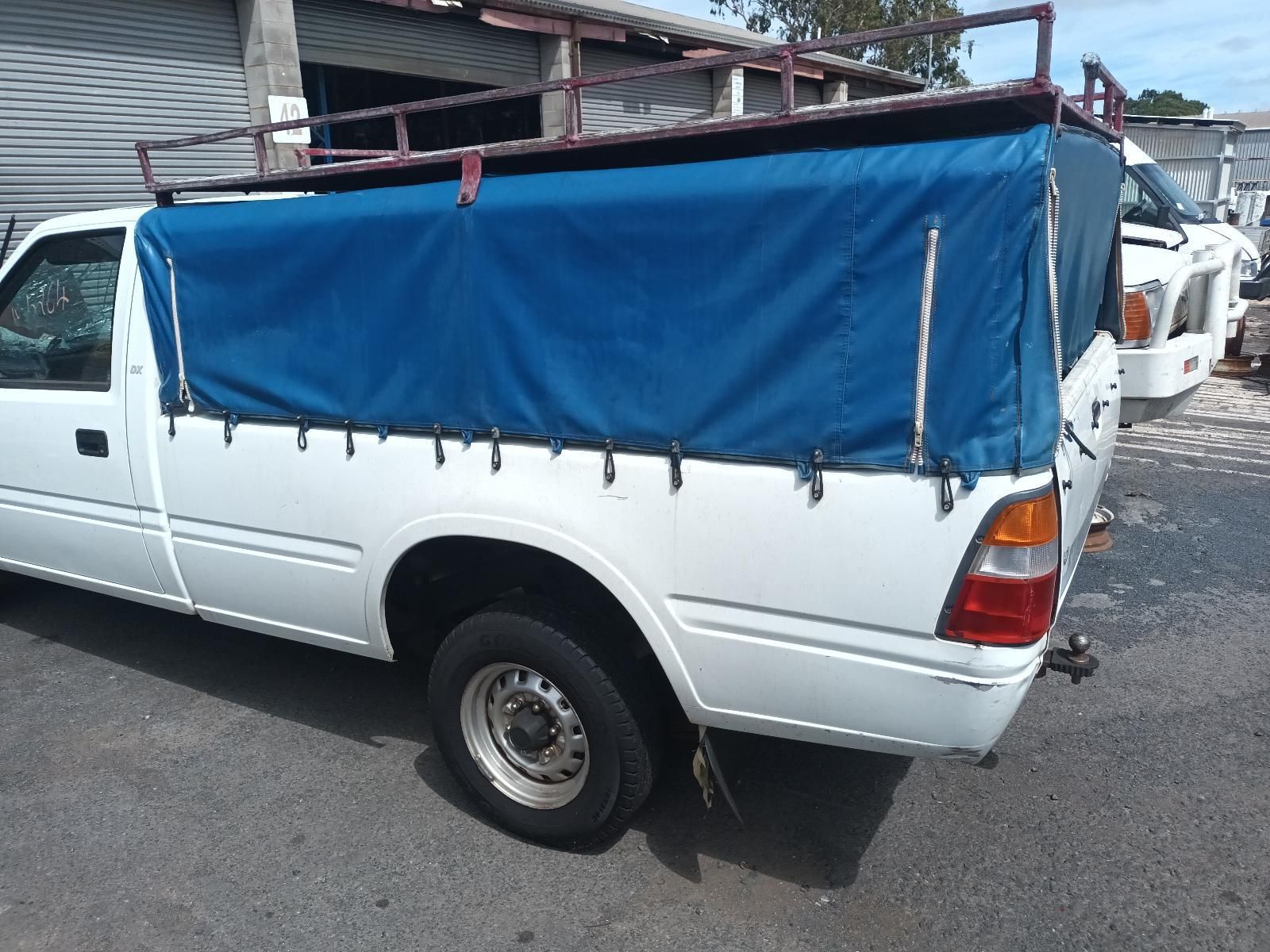 A White Truck with a Blue Tarp on the Back is Parked on the Side of the Road — South West 4WD Wreckers in Harristown, QLD