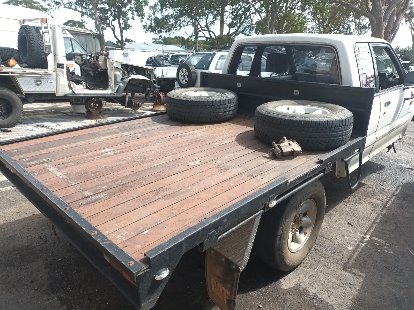A Flatbed Truck with Tires on the Back is Parked on the Side of the Road — South West 4WD Wreckers In Brisbane, QLD