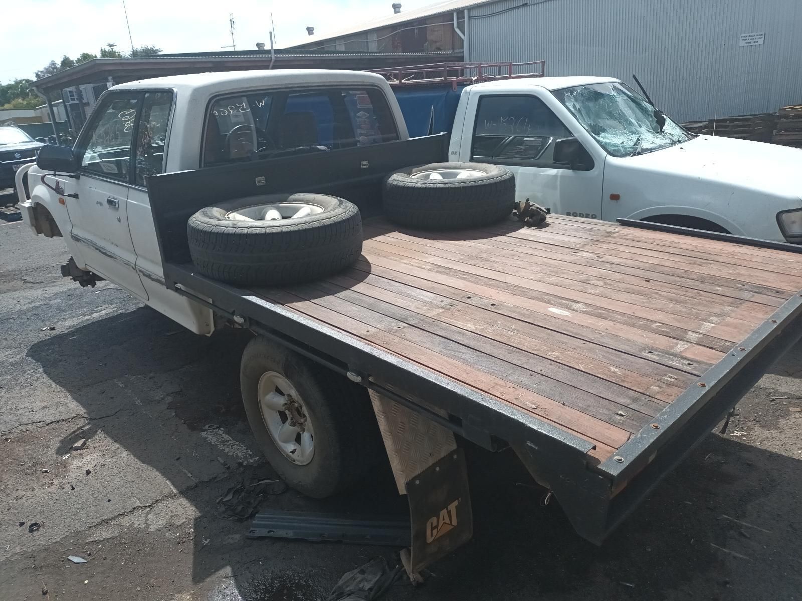 A White Truck is Parked Next to a Flatbed Truck with Tires on It — South West 4WD Wreckers In Brisbane, QLD