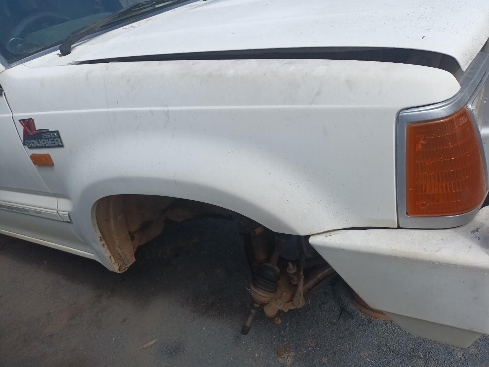 A White Truck with a Broken Fender is Parked on the Side of the Road — South West 4WD Wreckers In Brisbane, QLD