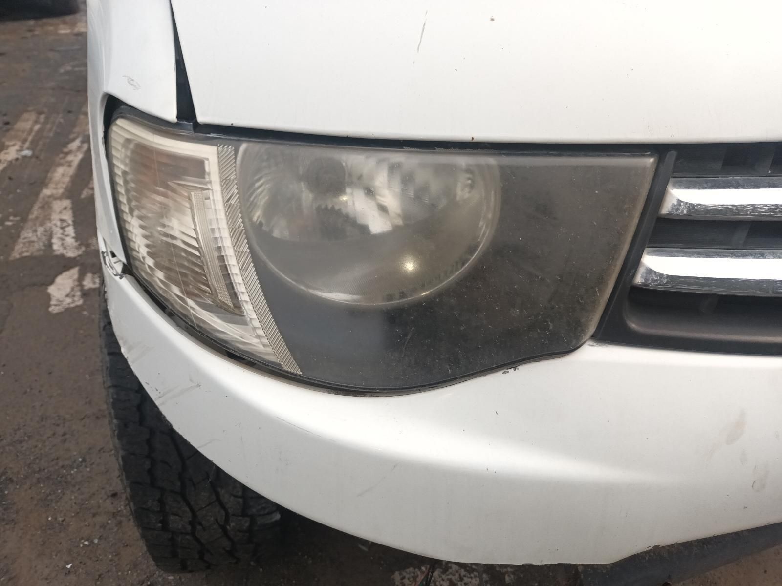 A White Car with a Broken Headlight is Parked on the Side of the Road — South West 4WD Wreckers In Brisbane, QLD