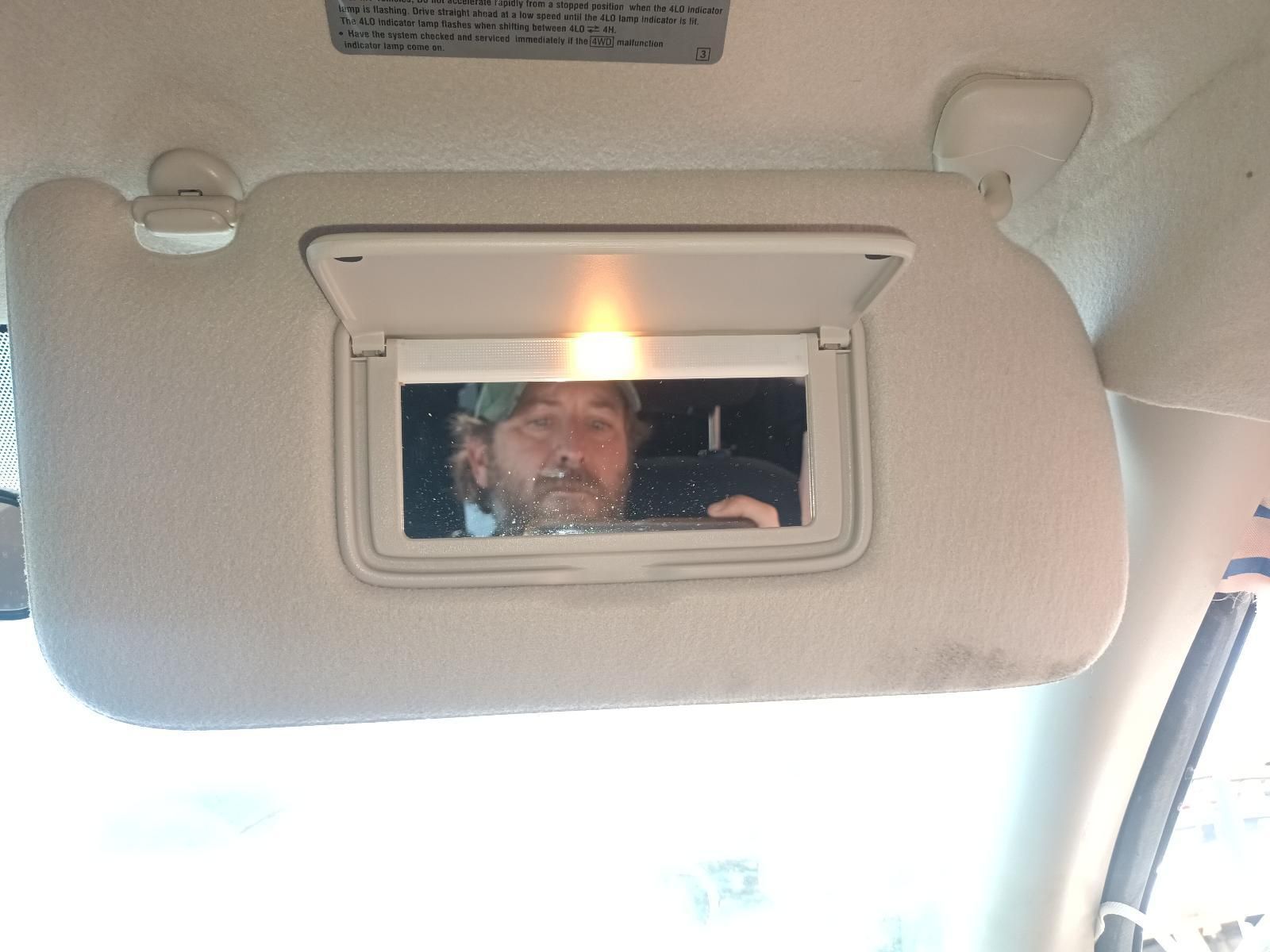 A Man is Taking a Picture of Himself in the Sun Visor of a Car — South West 4WD Wreckers In Brisbane, QLD