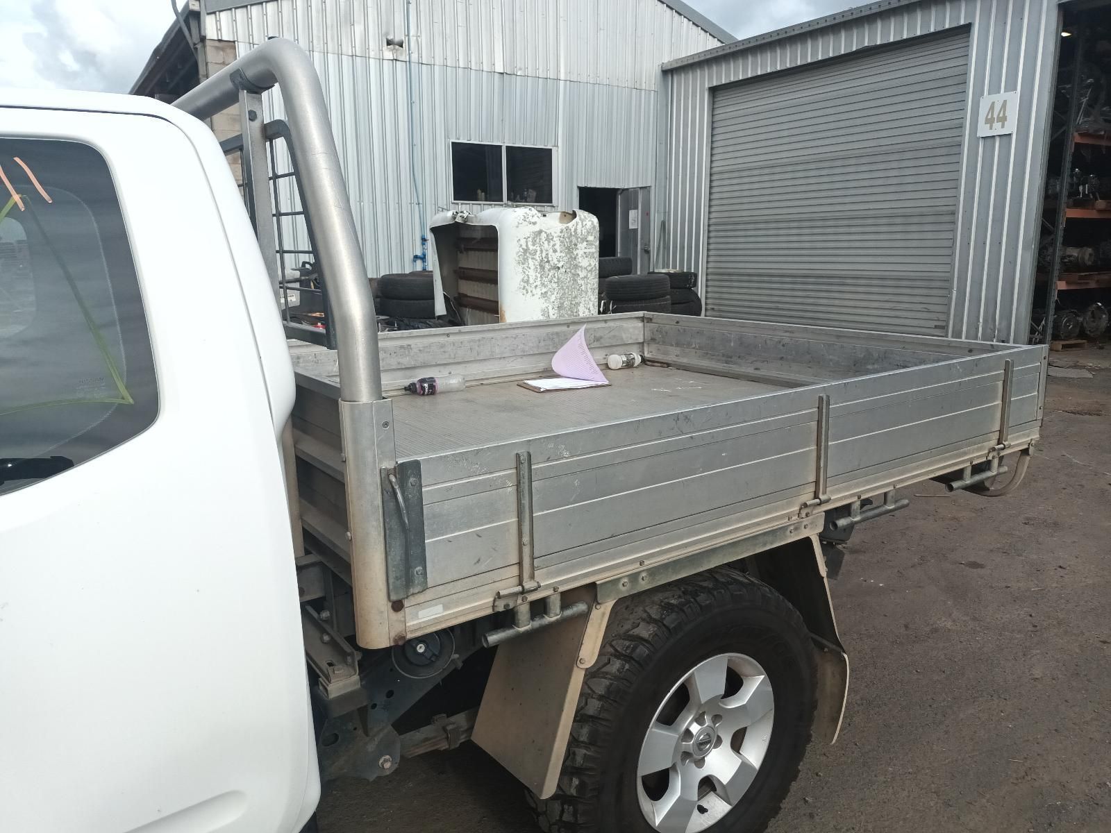 A White Truck with a Tray on the Back is Parked in Front of a Garage — South West 4WD Wreckers In Brisbane, QLD