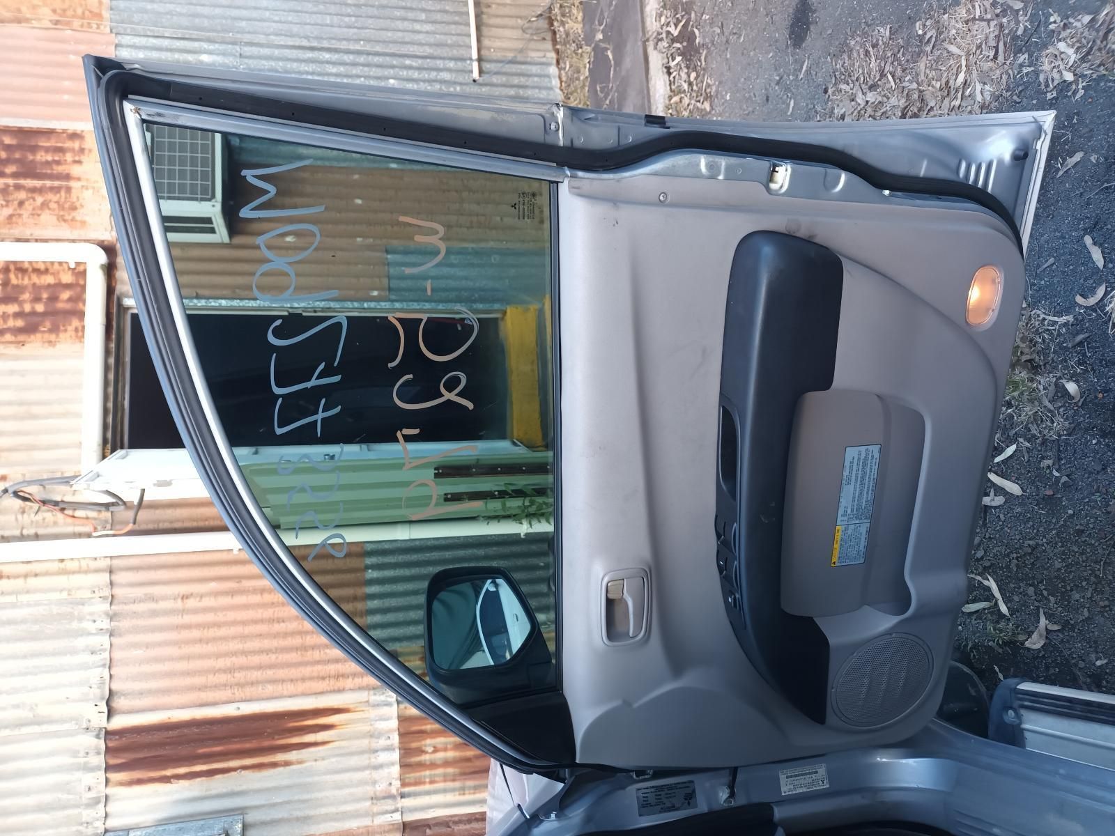 A Car is Parked in Front of a Rusty Building with the Door Open — South West 4WD Wreckers in Harristown, QLD
