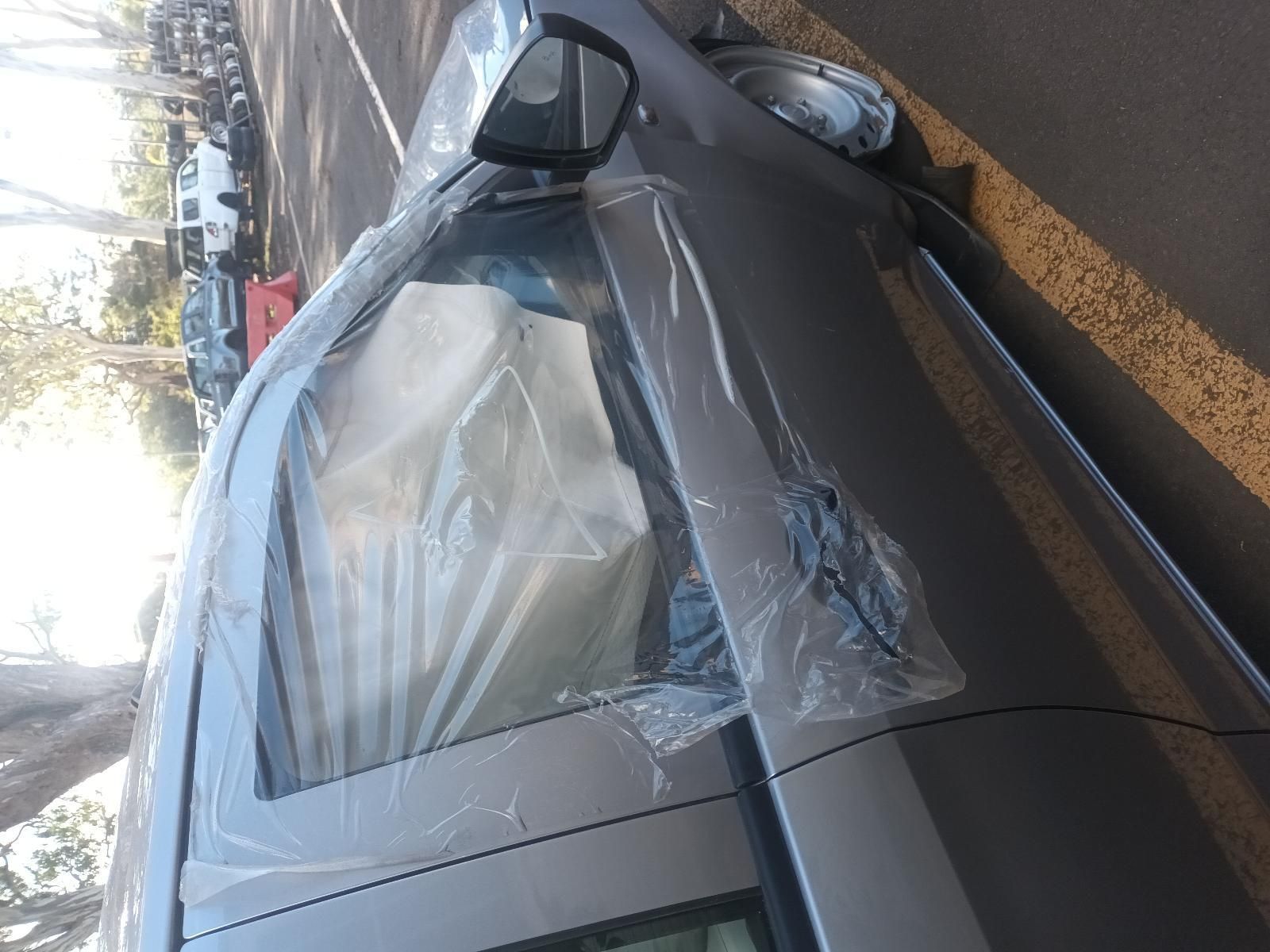 A Silver Car Wrapped in Plastic is Parked on the Side of the Road — South West 4WD Wreckers in Harristown, QLD