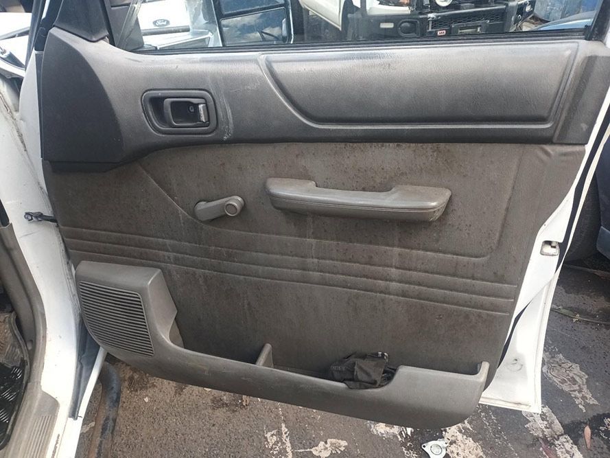 A White Car with a Black Door Panel is Parked on the Side of the Road — South West 4WD Wreckers in Harristown, QLD