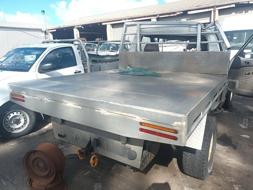A Truck with a Flat Bed is Parked Next to a White Truck — South West 4WD Wreckers in Harristown, QLD