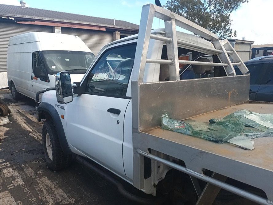 A White Truck with a Flat Bed is Parked Next to a White Van — South West 4WD Wreckers in Harristown, QLD