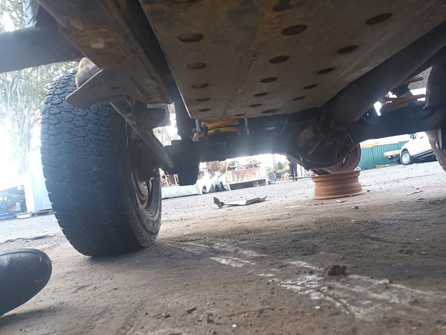 A Close Up of the Underside of a Car with a Tire on the Ground — South West 4WD Wreckers in Harristown, QLD