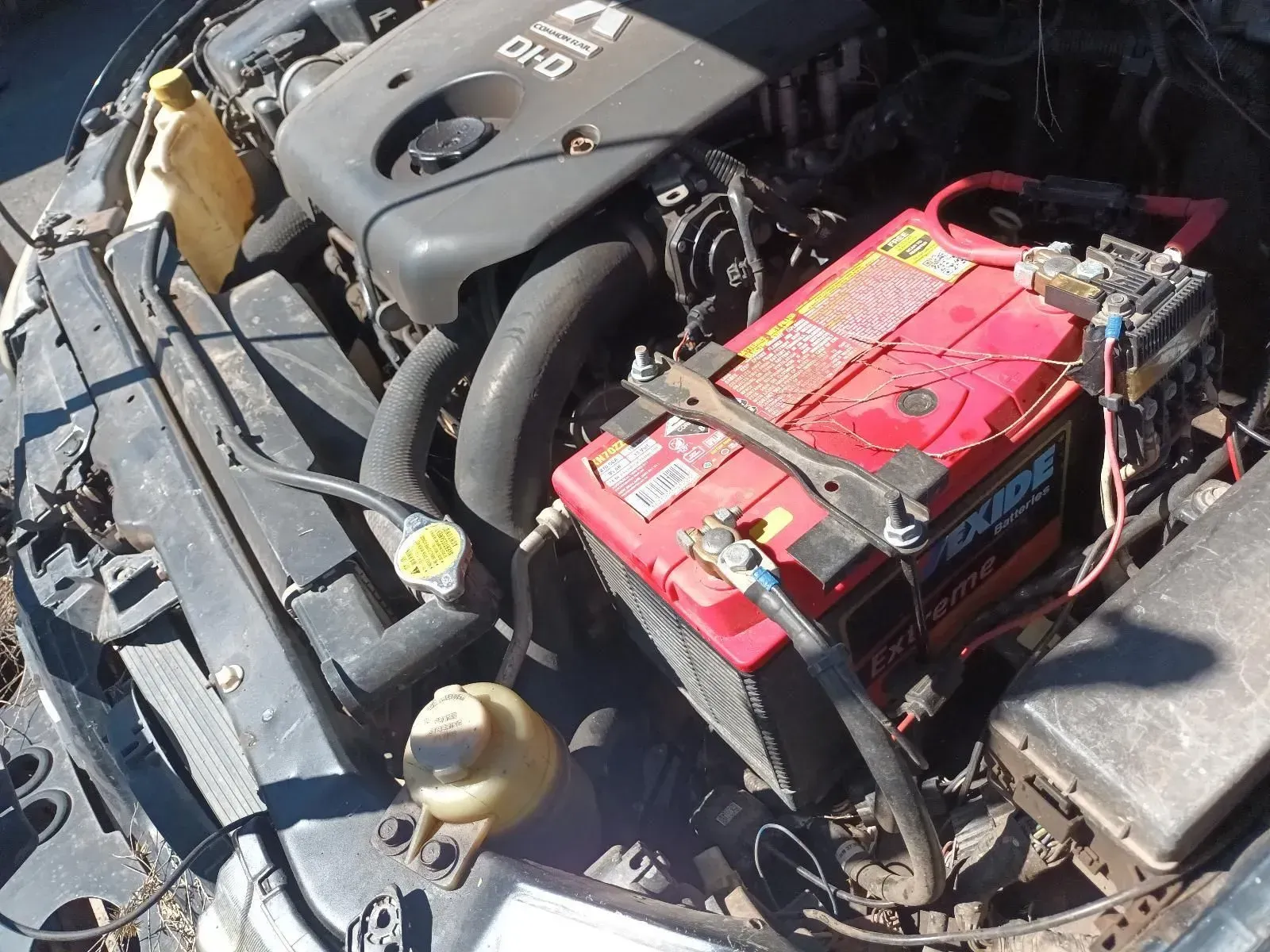 Car Engine Bay With Red Battery, Black Engine, and Yellow Fluid Reservoirs — South West 4WD Wreckers In Brisbane, QLD