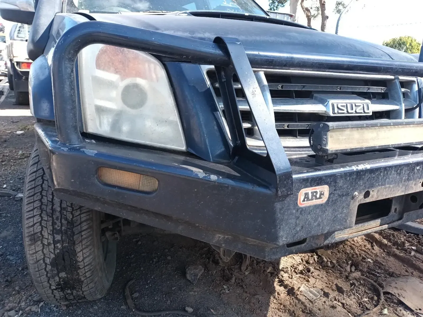 Dark Blue Isuzu Truck With Arb Bumper, Damaged Headlight, and Dirty Tyre — South West 4WD Wreckers In Brisbane, QLD