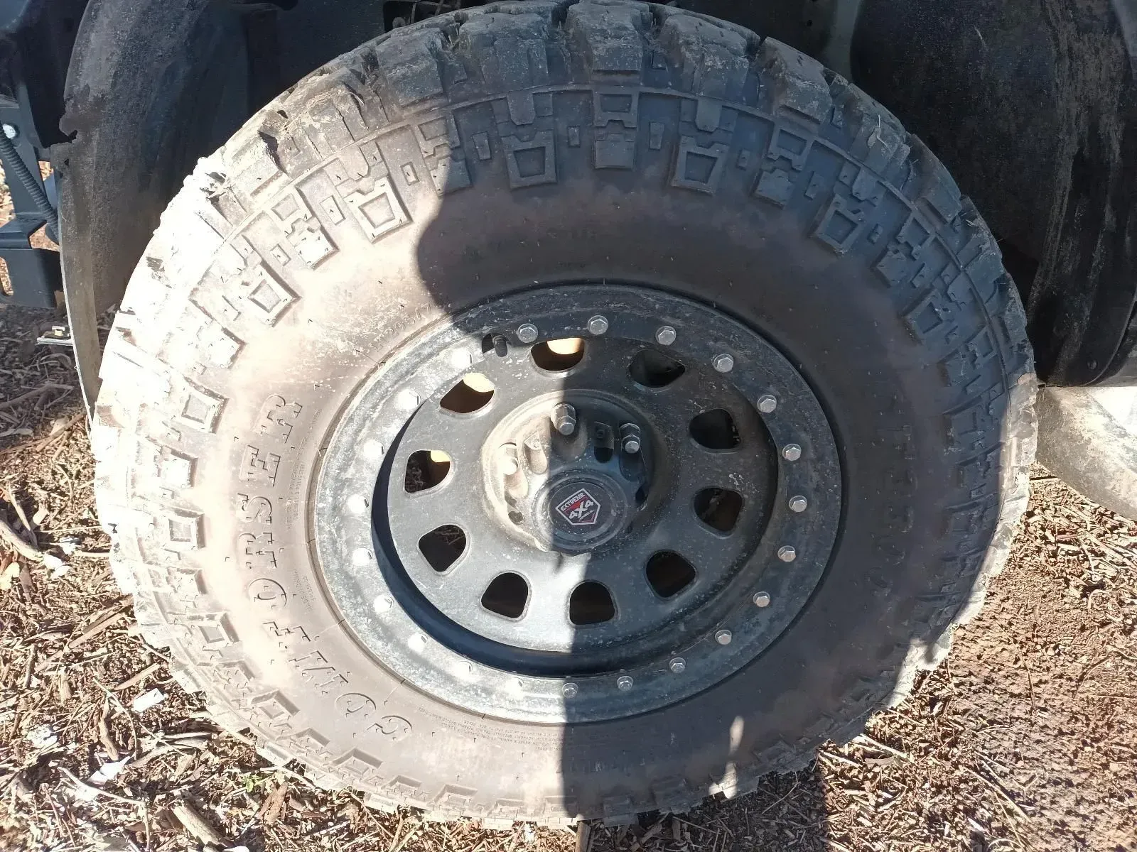 Black Off-road Tyre and Wheel With a Rugged Tread Pattern, Set Outdoors — South West 4WD Wreckers In Brisbane, QLD