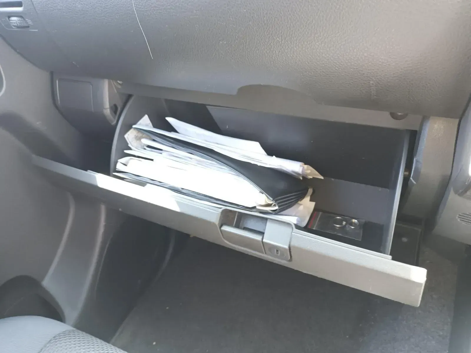 Opened Car Glove Compartment Holding Paperwork and a Small Remote — South West 4WD Wreckers In Brisbane, QLD