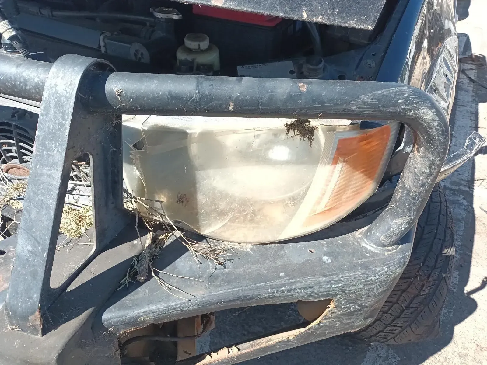 Close-up of a Damaged Car Headlight With a Black Bumper and Dirt and Debris — South West 4WD Wreckers In Brisbane, QLD